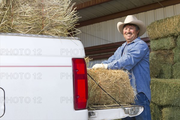 Hispanic man loading hay onto truck