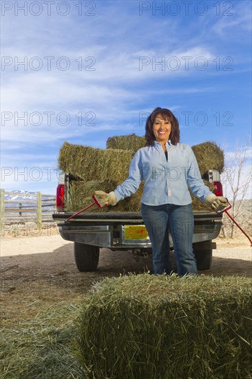Hispanic woman loading hay onto truck