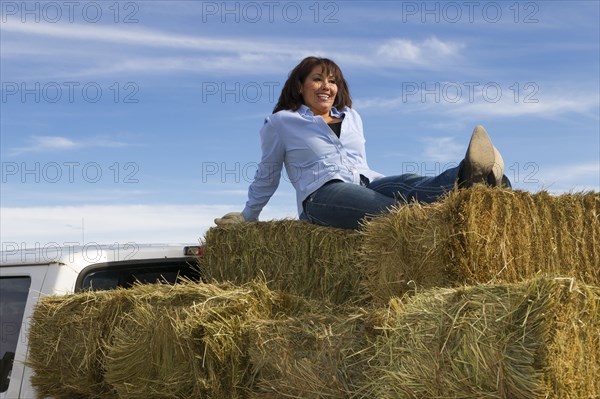 Hispanic woman sitting on hay bales