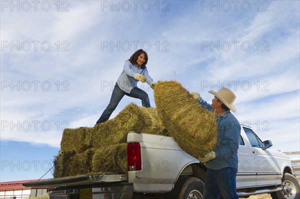 Hispanic couple loading hay onto truck