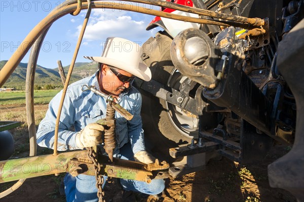 Hispanic farmer working on tractor