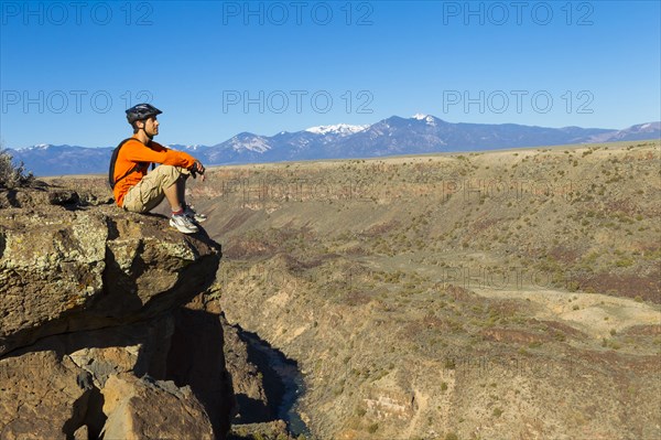 Hispanic man sitting on canyon cliff