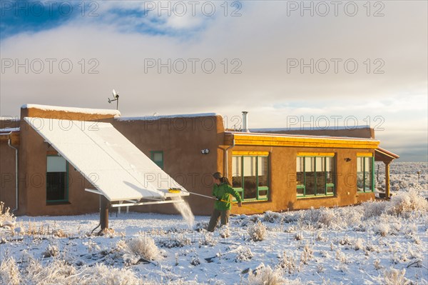Woman taking snow off solar panel