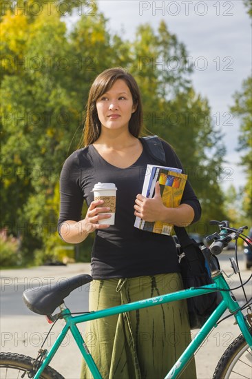 Alaskan woman carrying coffee and school books