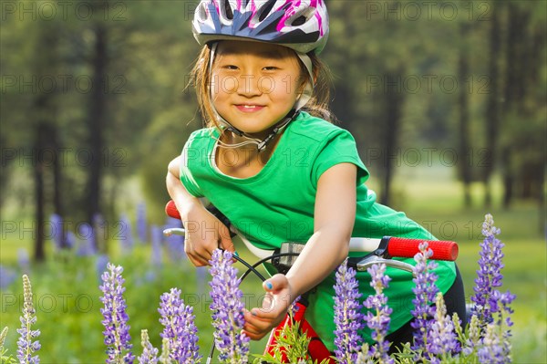 Asian girl sitting on bicycle in meadow