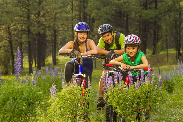 Family sitting on bicycles in meadow