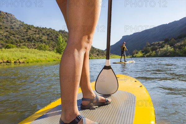 Hispanic woman riding paddle board