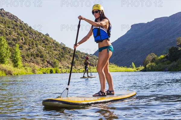 Hispanic woman riding paddle board