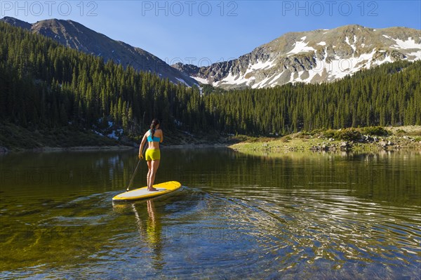 Hispanic woman riding paddle board