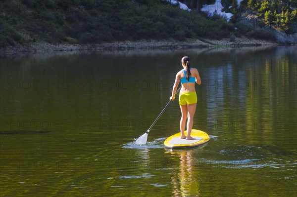 Hispanic woman riding paddle board