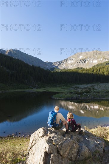 Caucasian hikers sitting on boulder