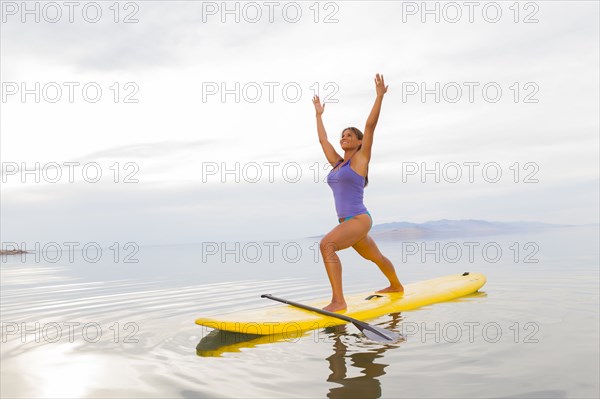 Filipino woman practicing yoga on paddle board