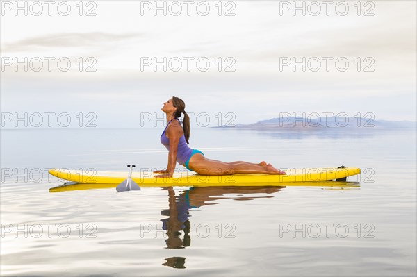 Filipino woman practicing yoga on paddle board