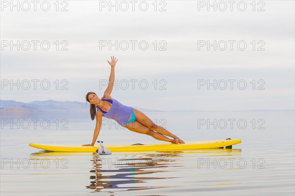 Filipino woman practicing yoga on paddle board