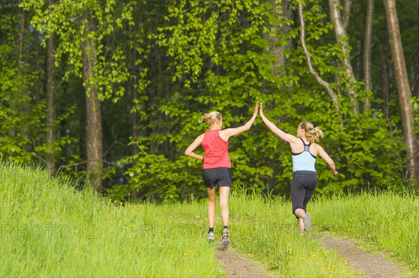Caucasian runners high fiving on path