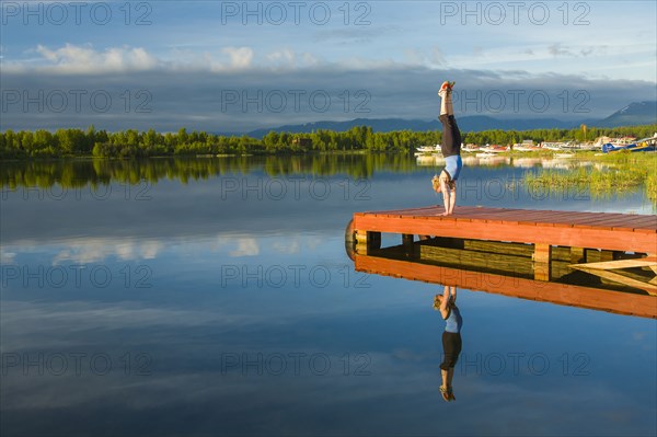 Caucasian woman practicing yoga on dock on still lake