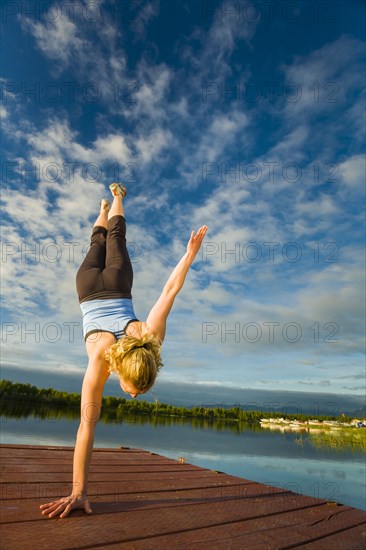 Caucasian woman practicing yoga on dock on still lake