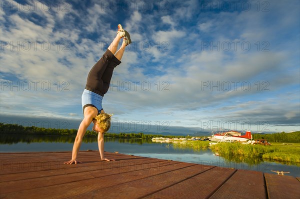 Caucasian woman practicing yoga on dock on still lake