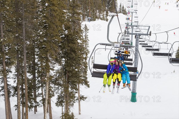 Girls riding ski lift on snowy slope