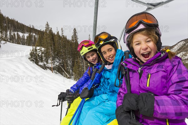 Girls riding ski lift on snowy slope