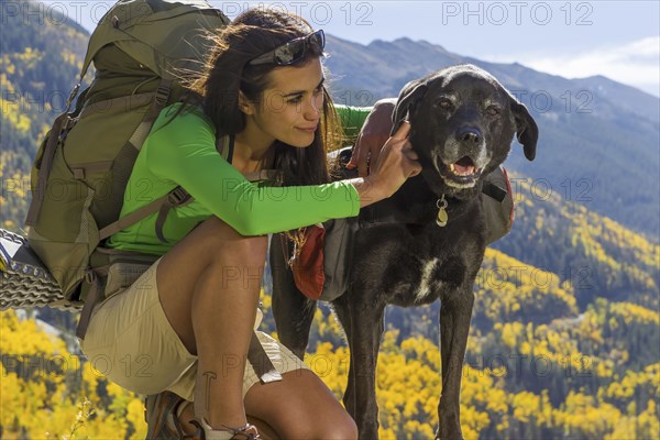 Mixed race woman petting dog on hilltop