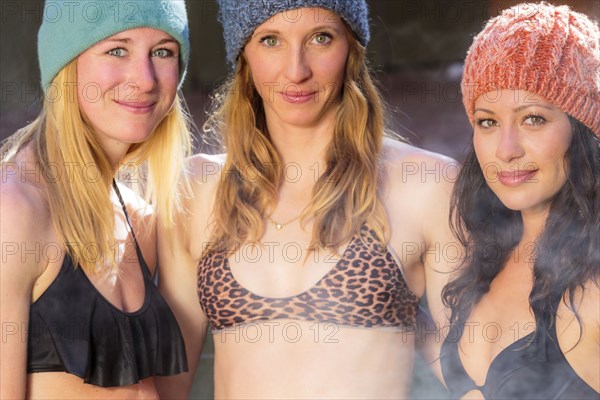 Women smiling in bikinis and beanie hats