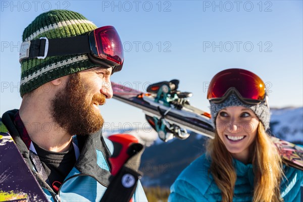 Couple carrying skis on snowy mountain