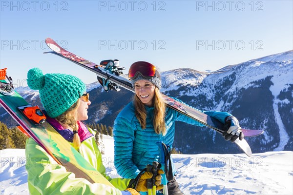 Women carrying skis on snowy mountain