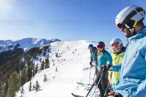 Friends on skis standing on snowy mountaintop