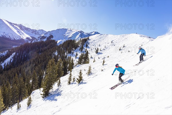 Couple skiing on snowy mountain slope