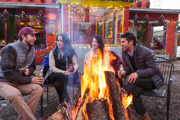 Couples drinking cocktails and beer outdoors at storefront campfire