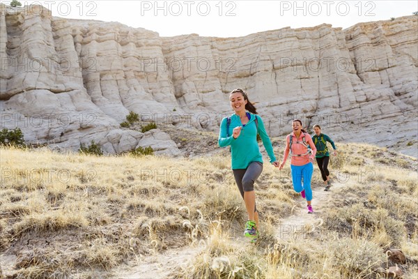 Women running in canyon wearing backpacks