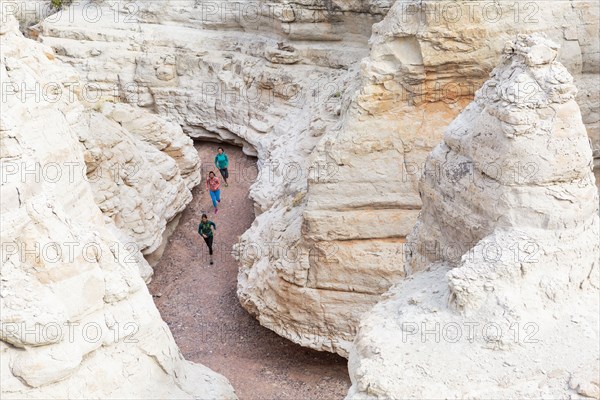 Women running in canyon wearing backpacks