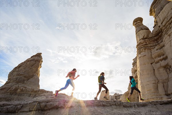 Women running in canyon wearing backpacks