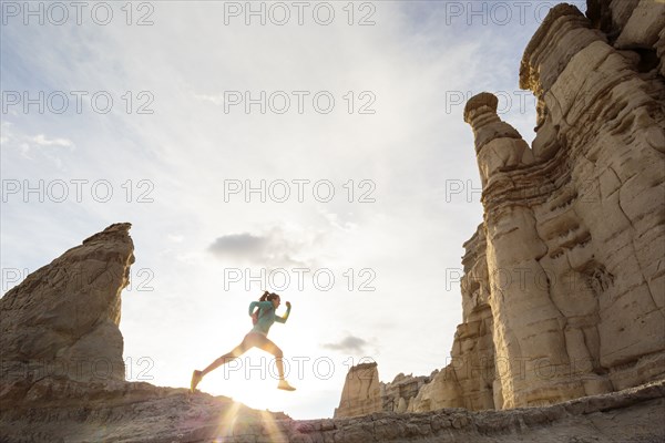 Woman running in canyon wearing backpack