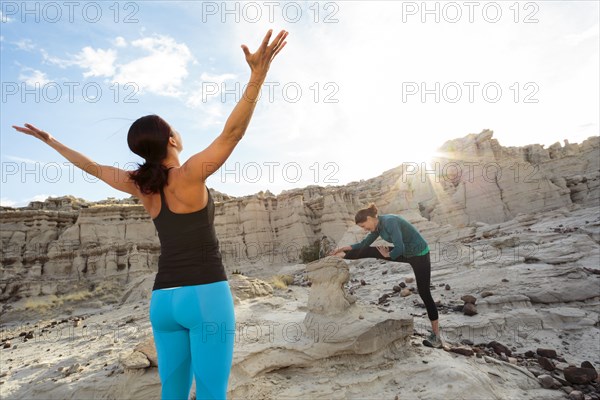 Women stretching arms and legs in canyon