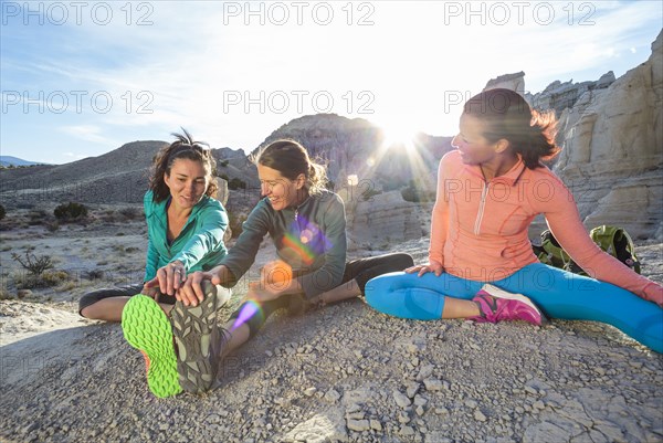 Women sitting in canyon stretching legs