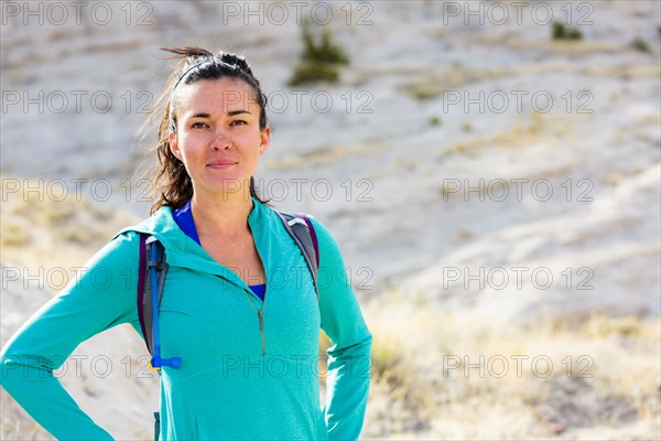 Confident woman standing in canyon wearing backpack