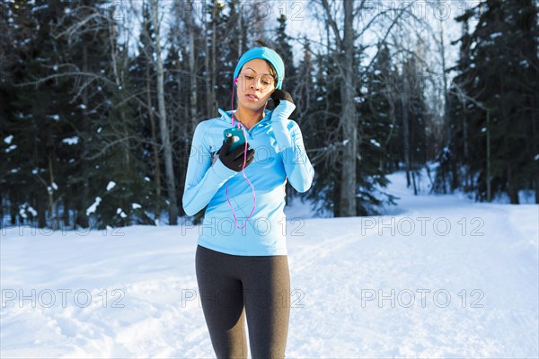 Black woman listening to cell phone with earbuds