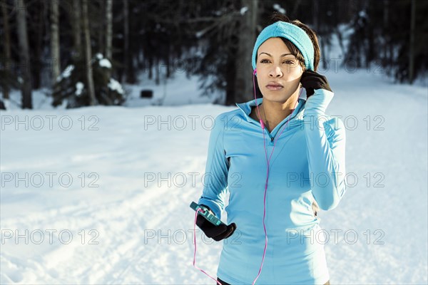 Black runner listening to cell phone with earbuds in winter