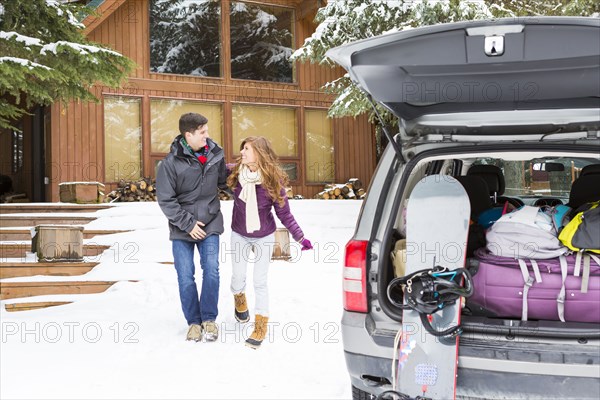 Caucasian couple walking to car at winter resort