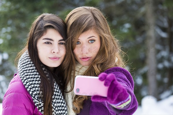 Women posing for cell phone selfie in winter