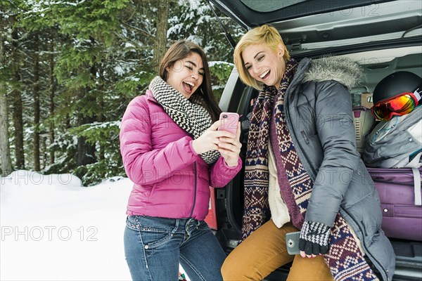 Women at car posing for cell phone selfie in winter