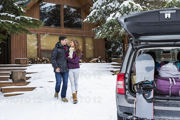 Caucasian couple walking to car with snowboards in winter