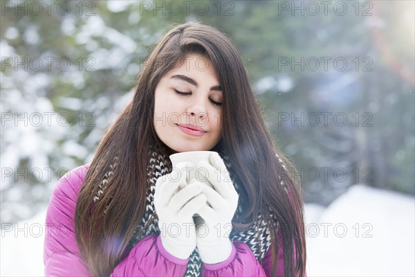 Mixed Race woman enjoying warm beverage in winter