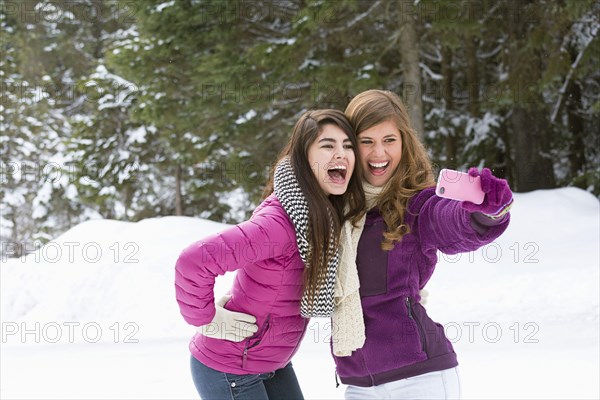 Women posing for cell phone selfie in winter