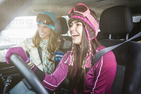 Women driving in car in winter and laughing