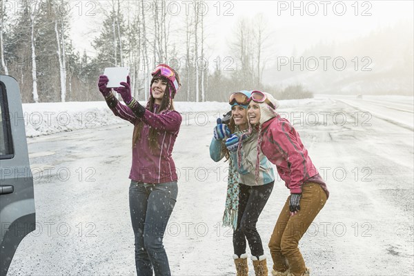 Women posing for cell phone selfie in winter using digital tablet