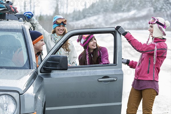 Friends laughing near car in winter