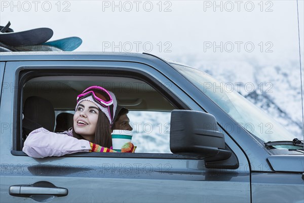 Mixed Race woman leaning on car window in winter